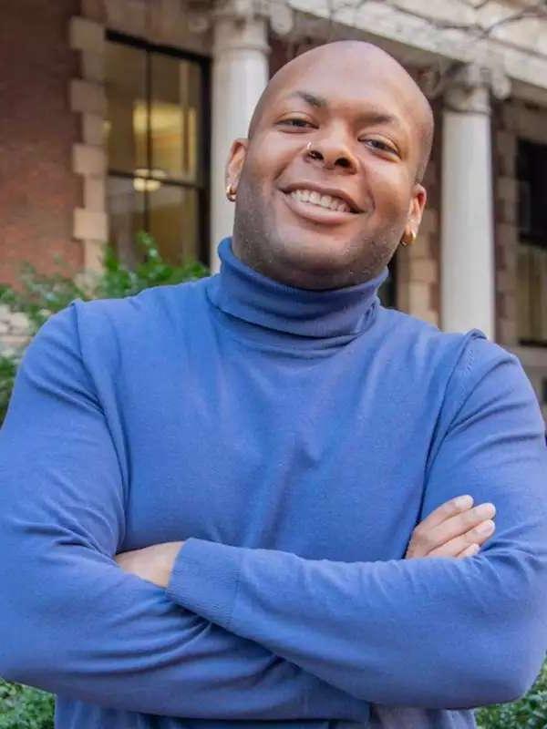 mixed background with man smiling with arms crossed, wearing a blue turtleneck 